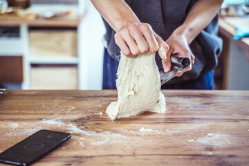 Young male home baker preparing artisan sourdough bread dough.
