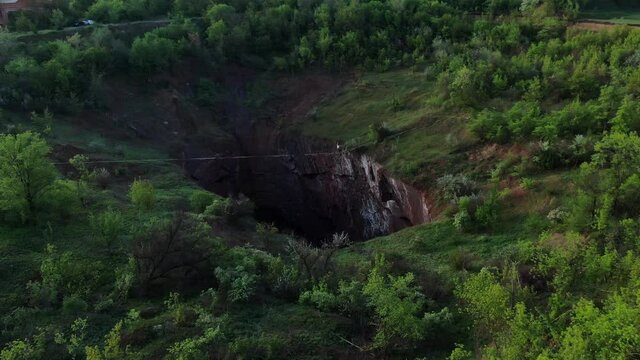 Gorgeous view on the nature around the massive pit and a man slacklining, 4k