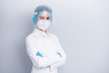 Photo of beautiful confident virology doctor lady arms crossed serious professional nurse wear medical coat mask facial plastic protection shield surgical cap isolated grey background