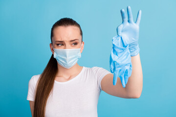 Closeup photo of beautiful negative lady hold dirty surgical latex gloves afraid infections disgusted expression wear protect face mask white t-shirt isolated blue color background