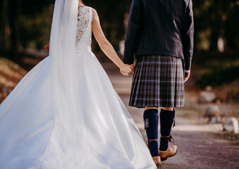 Obraz na płótnie Canvas Bride and groom walk away hand in hand