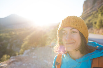 Portrait of a smiling girl with a backpack on a background of mountains.