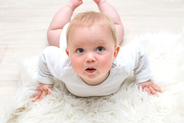 Little baby boy crawling on the floor and looking upwards, baby and white background is wondering
