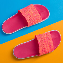 pink slippers on blue and yellow background, concept of summer vacation