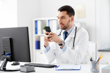 healthcare, medicine and people concept - male doctor with smartphone at hospital