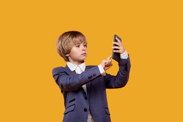 A little boy uses a mobile phone. A boy in a white shirt.