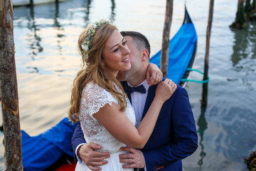 beautiful wedding couple posing on dock near blue gondolas