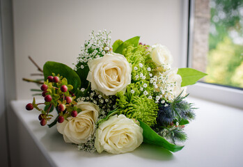 Cream bouquet of roses, berries and thistles in window