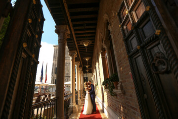 Obraz na płótnie Canvas beautiful bride and handsome groom posing in streets of venice