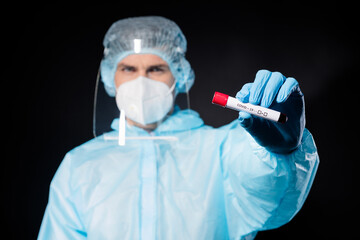 Closeup photo of doc virologist guy hold blood probe test tube virus vaccination research wear gloves respirator hazmat surgical cap plastic facial shield isolated black color background