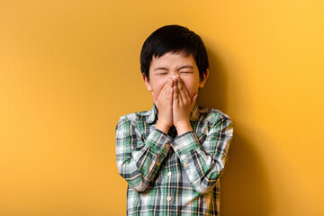 sick asian boy sneezing on yellow during quarantine