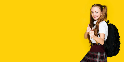Banner format, elementary pupil student schoolgirl showing thumb up and smiling on yellow background