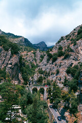 Fototapeta na wymiar View of the old bridge made of stone. Between the steep mountains. Marina di Praia. Mountain landscape coast of Italy, Amalfi. Sea and rocks, Tourists and vacations in Europe. Vertical photo