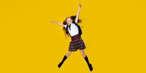 Fototapeta na wymiar Full length photo of caucasian funny little schoolgirl pupil jump in uniform with backpack on vibrant yellow background, back to school, learning education concept