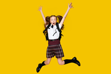 Fototapeta na wymiar Full length photo of little funny crazy little lady schoolgirl pupil jump in uniform with backpack on vibrant yellow background, back to school, learning education concept