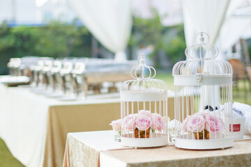 White and blue cup cake on wooden table in wedding ceremony with flowers outside in the garden. garden party set up for lunch dinner with long table folding chairs and flowers.