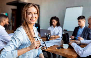 Businesswoman Smiling Sitting On Meeting With Coworkers In Office