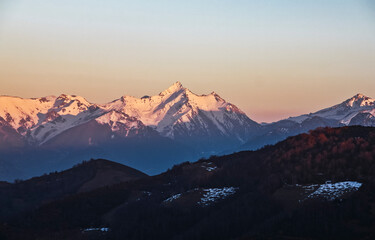 Landscape of high mountains covered by snow in a sunset with the sun hitting the peaks and the shade in the valleys