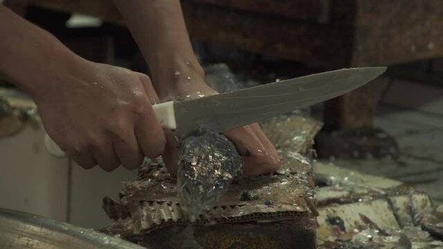 A fishmonger chopping a fish's head at the Central Fish Market in Manama, Bahrain