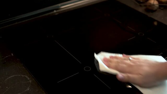 Hand view for cleaning the black induction hob by white paper towel  at home