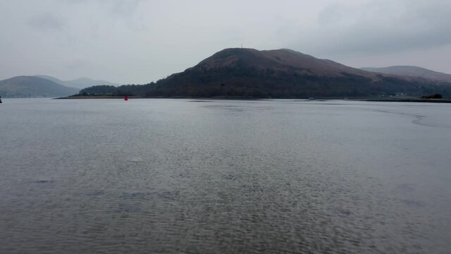 Drone footage of a lake in scotland (Loch Eil). Corpach, near Fort William, Scottish highlands. Forwards motion, late autumn, cloudy with distant mist. no people.