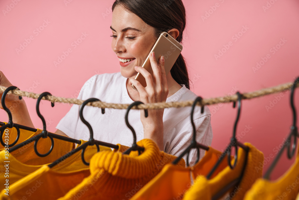 Sticker Photo of woman talking on mobile phone while standing at clothes rack