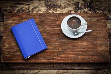 Blue daily planner and a white cup of coffee on a wooden background, top view, table, copy space