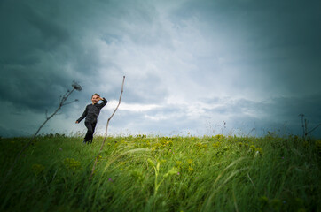 The boy runs across the field - soon it is raining, the wind is blowing, bending the grass, but he...