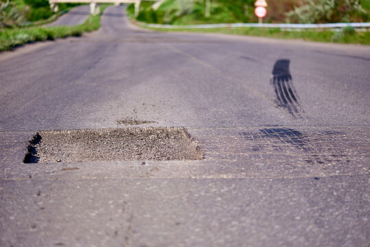 A Pit On A Roadway With A Car Trail From Sudden Braking.