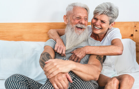 Mature couple enjoying time together at home after waking up - Senior man and woman having tender moments sitting in bed - Love and joyful elderly lifestyle concept - Main focus on wife face