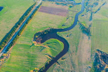 Aerial landscape of winding meanders small river, stream in green field, top evening sunset view meadow.
