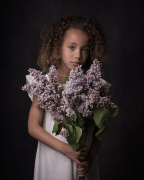 Portrait of girl holding bunch of flowers while standing indoors