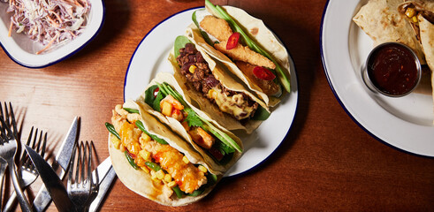 mexican food banner, quesadilla, sauce, salad, knives, forks, burrito on wood background