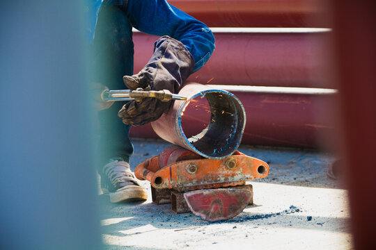 Welder with protective  leather gloves cutting member of steel pipe with a gas torch. 