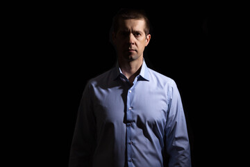 confident serious man in a shirt, looking into the camera, isolated, on a black