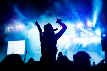 Silhouette of girl with raised hands on music concert