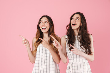 Image of excited caucasian women smiling and pointing fingers aside