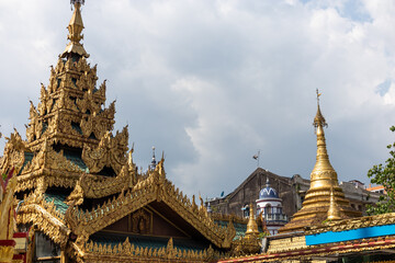 Fototapeta premium Representation of two religions in Myanmar: roofs of the buddhist Sule pagoda pictured from the inside. Muslim mosque at the background. Yangon - Rangoon, Myanmar, Burma, Southeast Asia