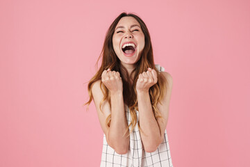 Image of excited beautiful woman screaming and making winner gesture