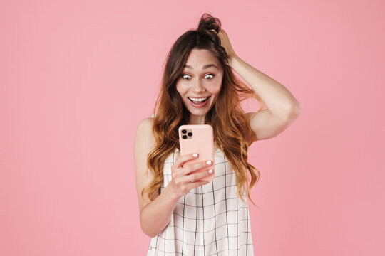 Image of excited cute woman using cellphone and expressing surprise