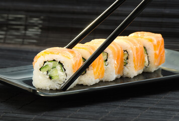 Philadelphia Sushi with chopsticks on black dish