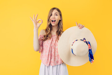 excited shocked woman in a summer hat, makes a good gesture, says good, confirms the information, on a yellow background