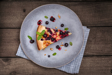 A piece of blackcurrant pie on a grey plate decorated with mint leaves