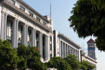 Fototapeta na wymiar Official colonial building, restored facade. White building with high columns, Asian city. Yangon - Rangoon, Myanmar - Burma, Southeast Asia