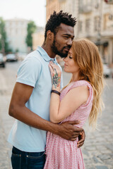 Obraz premium Interracial Relations. An African man and a Caucasian woman stand embracing on a city street.