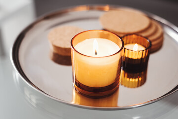 Burning aroma candles of warm yellow color on a metal tray. Home aromatherapy. Simple decor. Cozy atmosphere