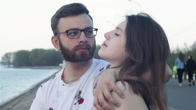 beautiful young female and male with a beard sitting together near the sea and talking, laughing. man and woman having relationships, real emotions. Love story. Romantic, cute, funny moments