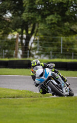 A shot of a white and blue racing bike cornering as it circuits a track