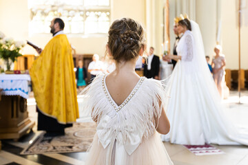 Naklejka premium Little girl in a dress. She stands with her back. In the church.