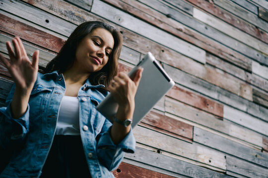 Below view of attractive young woman watching funny videos in social networks on modern tablet.Cheerful female doing shopping online on internet website on digital touch pad.Copy space area for text